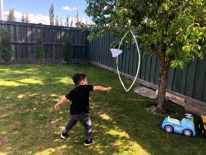 child throwing paper airplane through hoop