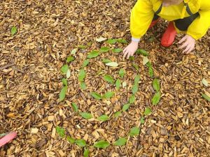 Child Creating Fall Leaves Design on Ground