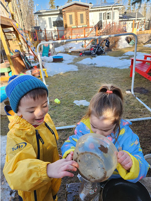 Boy and girl playing in the outdoor mud kitchen.