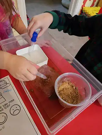 children adding salt and sugar to the ice in the bins