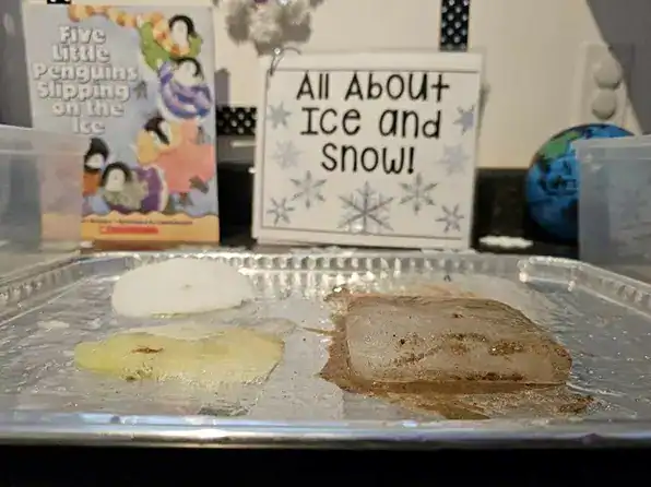 Ice mixed with salt, sugar, and sand melting on a tin tray