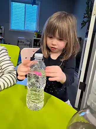 child looking into a bottle containing a floating seahorse